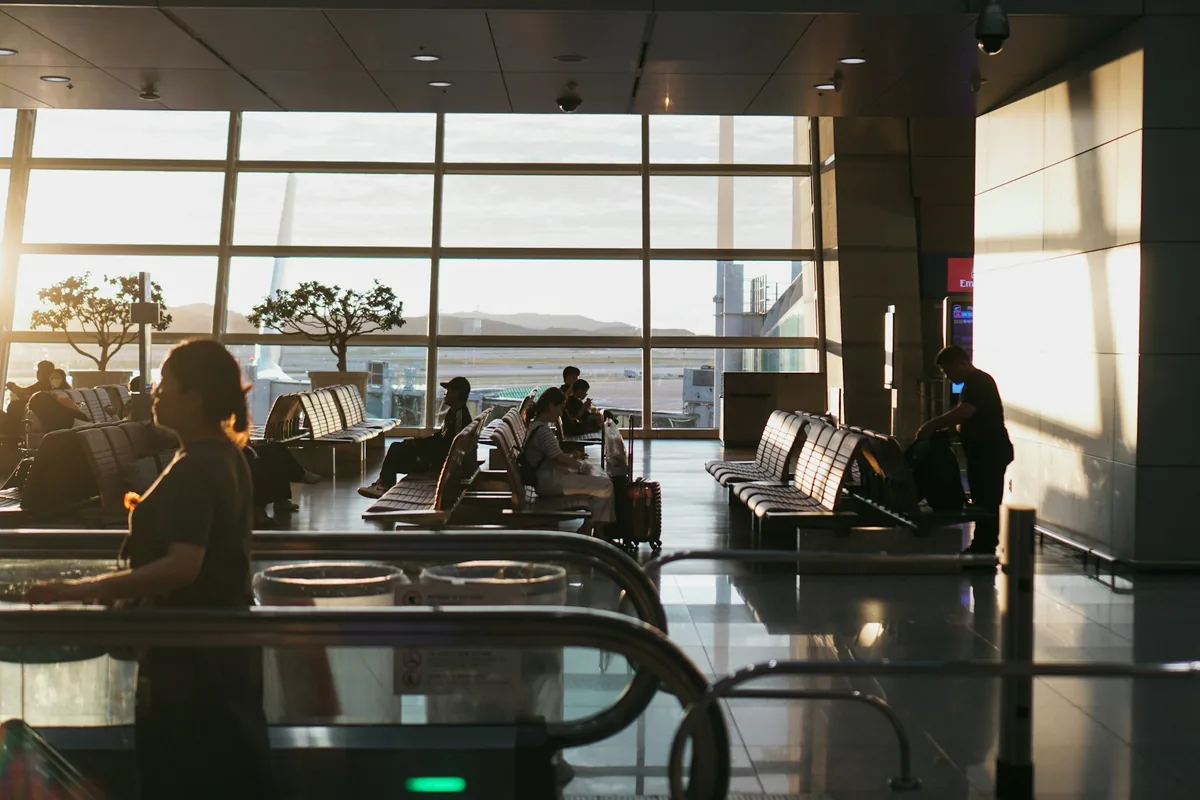 Passengers and rows of seats beside large windows at Incheon International Airport