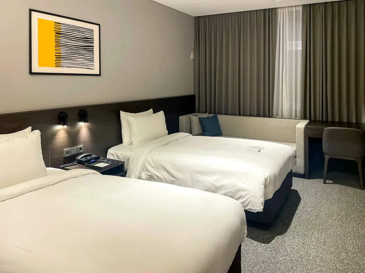 Two white beds and a sofa in a hotel room in Pangyo, Seongnam