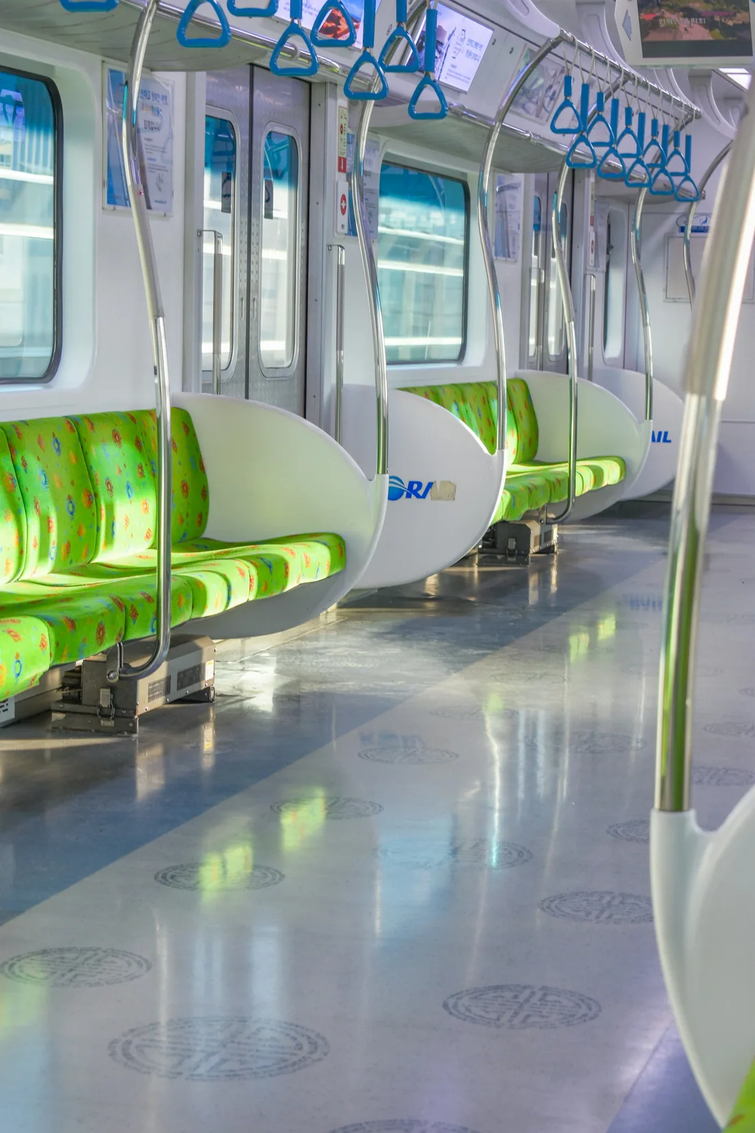 Green bench seats and blue hand straps inside a Seoul subway train