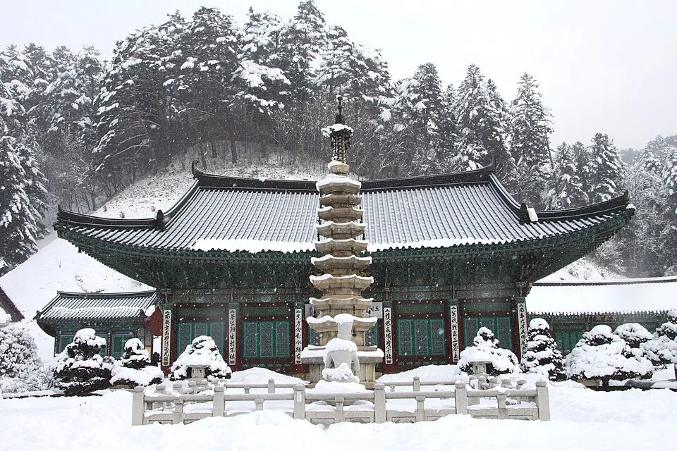 Snow-covered pagoda and hall at Woljeongsa Temple